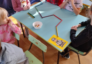 Dzieci siedzą przy stoliku i wykonują zadanie
