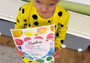 Dziewczynka trzyma dyplom za dzień kropki.