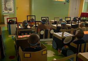 Dzieci siedzą w samochodach wykonanych z kartonów i oglądają seans filmowy z okazji Dnia Przedszkolaka