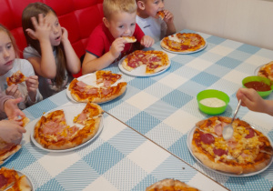 Dzieci próbują upieczonej pizzy.