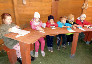 Dzieci czekają na instrukcje wykonania laleczki z kawałków materiałów.