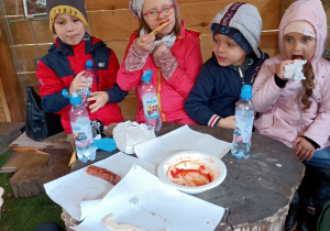 Krzyś, Lena, Igor i Lisana zajadają pyszną grillowaną kiełbaskę.