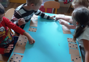 Dzieci kolejno rzucają kostką i zakrywają odpowiednie kartoniki