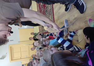 Dzieci głaszczą agamę brodatą.