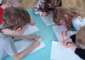 Dzieci poprawiają po śladzie rysunki drzew