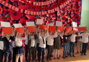 Dzieci z grupy VIII śpiewają piosenkę i wznoszą flagę Polski w górę