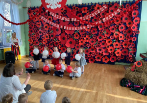 Dzieci z grupy II śpiewają piosenkę, trzymają w dłoniach biało - czerwone balony