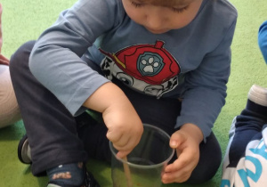 1.Chłopiec barwi wodę przy użyciu czerwonej bibuły