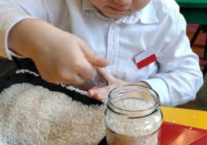 7.Chłopiec wsypuje biały ryż do słoika