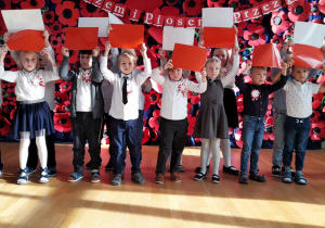 Dzieci układają flagę Polski z kartek jako część choreografii.