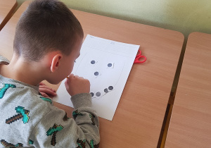 Chłopiec układa twarz z kropek za pomocą słomki