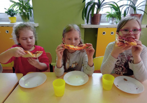 Zuzia, Liwia i Lena zajadają się pyszną pizzą.