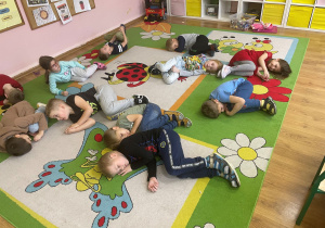Dzieci leżą na dywanie, naśladując kukurydzę