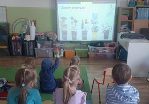 Dzieci oglądają prezentację multimedialną na temat segregacji śmieci