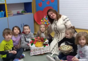 Anastazja pokazuje dzieciom naczynie służące do potraw na Ukrainie a Martynka pozuje do zdjęcia.