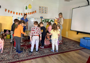 Dzieci z grupy Rybek zdmuchują piórka z dłoni w rytm muzyki