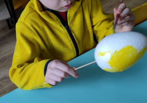 Zdjecie 5 - Chłopiec maluje jajko żółtą farbą