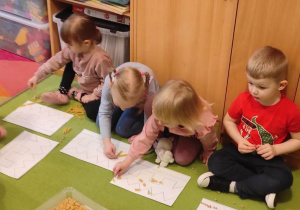 4.Dzieci staranie wykonują zadanie ułożenia szlaczków przy pomocy materiałów sypkich