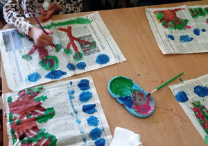 Dzieci malują wiosenne drzewa na gazetach