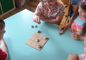 Dzieci grają w kółko-krzyżyk kamieniami