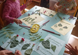 Dzieci przyklejają kwiaty i liście