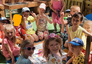 Dzieci siedzą wokół gry planszowej i poznają ciekawe Miejsca w Łodzi