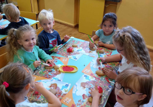 Dzieci malują połówki ziemniaków na czerwono