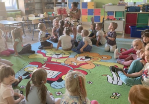 Dzieci siedzą w kole i słuchają opowiadania Kolorowy potwór na temat emocji
