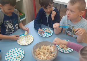 Dzieci jedzą własnoręcznie przygotowaną sałatkę.