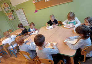 Dzieci piszą literki na tackach gdzie znajduje się kasza manna