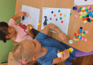 5.Dziewczynki przyklejają kolorowe kropki jako bańki mydlane.