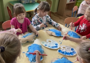 Dzieci malują niebieską farbą wypchane chmurki