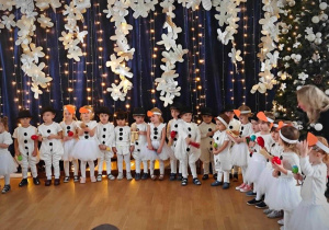 Zdjęcie grupowe przedstawiające dzieci stojące na tle dekoracji.