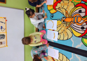 Dzieci z materiałów sypkich układają wzór spirali.