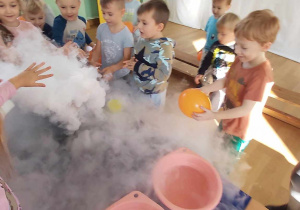 Dzieci z zaciekawieniem przyglądają się powstawaniu dymu.