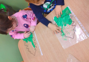 Dzieci wypełniają kontur choinki farbą z brokatem