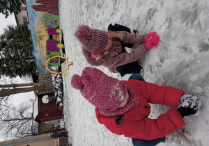 Dziewczynki lepią kule śniegowe.