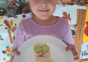Hania z uśmiechem pokazuje kanapkę w kształcie buzi.