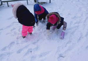 Dzieci lepią kule śniegowe.