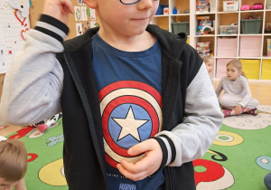 Chłopiec wykonuje zadanie "U jak ucho słyszy" - potrząsa pudełeczkiem, w którym ukryte są drobne elementy i rozpoznaje co to za przedmiot.