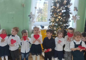 Dzieci z grupy Kotków pozują do zdjęcia z czerwonymi serduszkami.