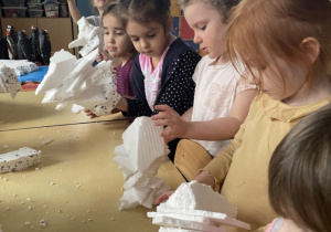 Dzieci tworzą styropianowe góry lodowe - nabijając kawałki styropianu na patyczek do szaszłyków