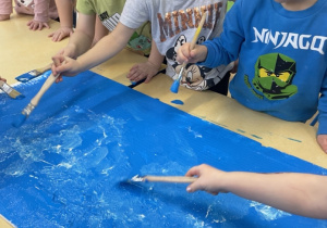 Dzieci malują styropian na niebiesko , który będzie imitował wod