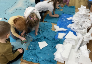 Dzieci układają na tablicy korkowej kolejne elementy makiety Antarktydy.