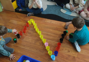 Dzieci za pomocą piłeczek układają literkę Z