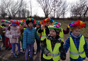 Dzieci w kolorowych ubraniach i barwnych kwiatowych wiankach na głowach pozują do zdjęcia.