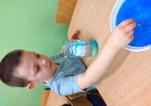 Chłopiec nabiera za pomocą pipety niebieski barwnik.