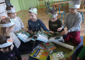 Dzieci oglądają albumy, książki o dinozaurach.