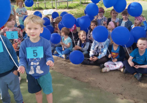Dzieci trzymają niebieskie balony.