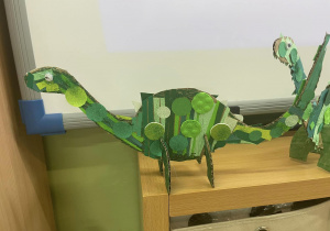 Figurka dinozaura wykonana z tektury i kolorowych papierów i pianek.